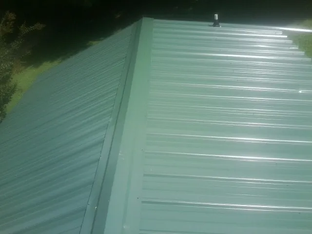 New green metal panels meeting at the ridge of a roof — Flat Roof Repair work by our crew in Black Eagle