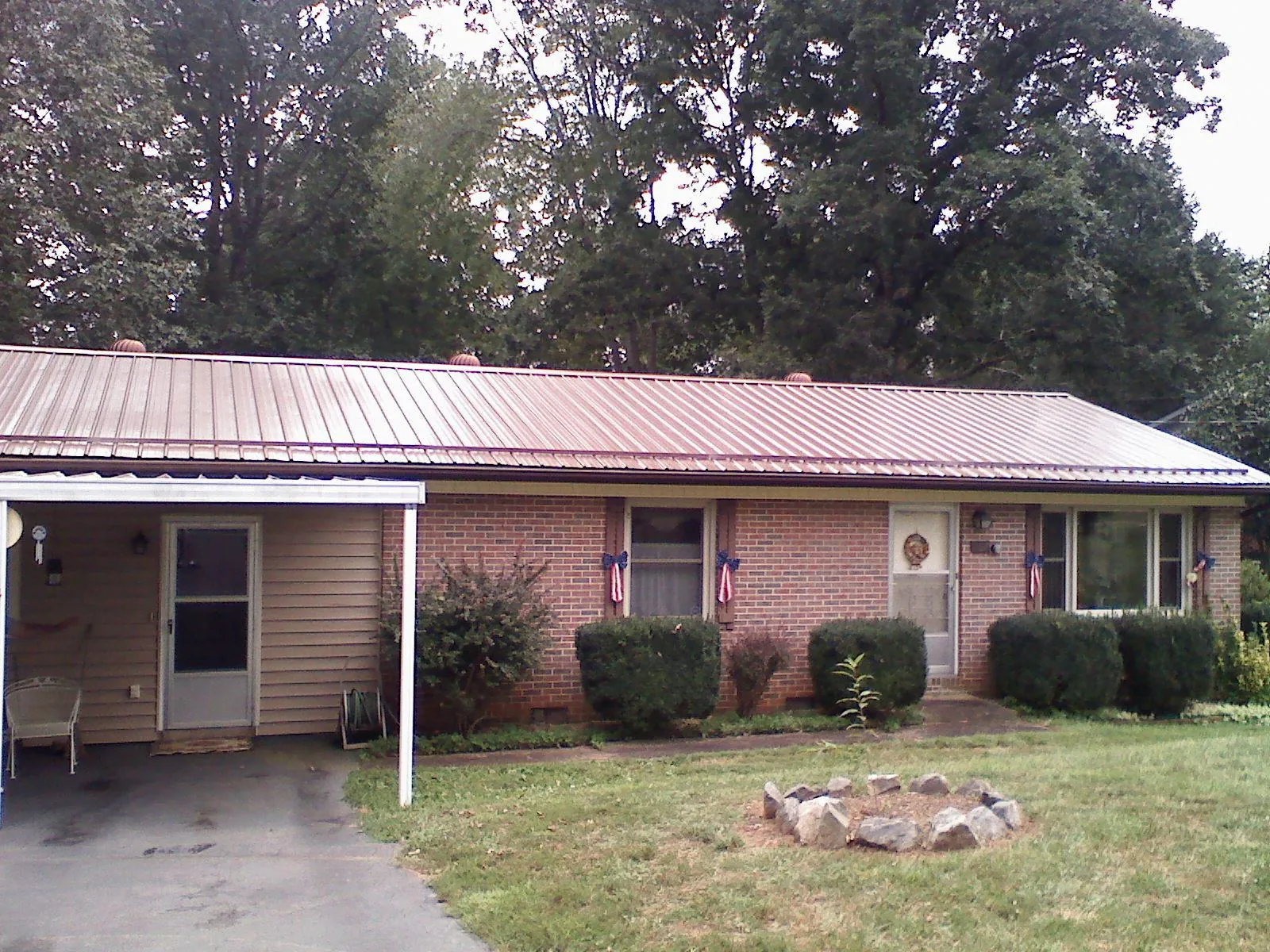 Bronze metal roof and carport on a brick ranch home — Roof Repair work by our crew in Black Eagle