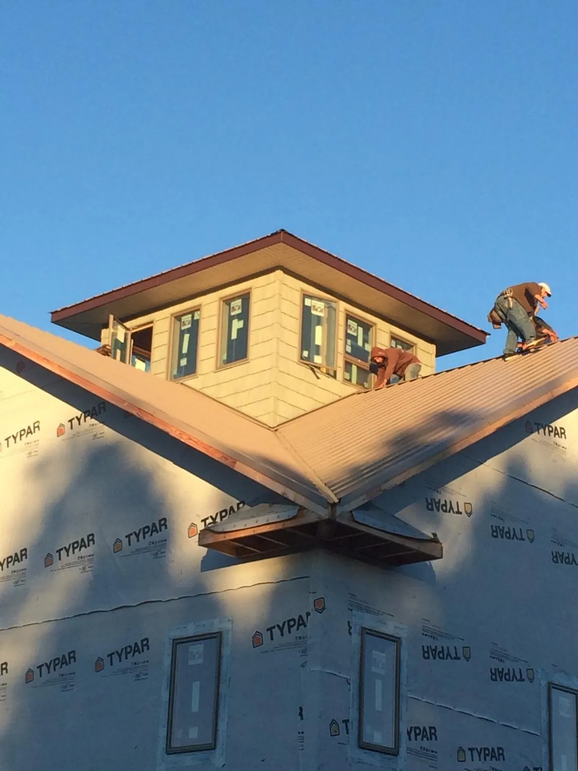 Roofers working around a rooftop cupola on a new metal roof at sunset — Roof Waterproofing in Black Eagle by Roofing Brothers